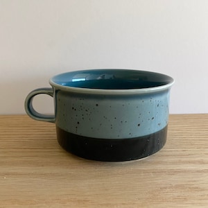 May include: A blue and black speckled ceramic mug with a wide rim and a handle.