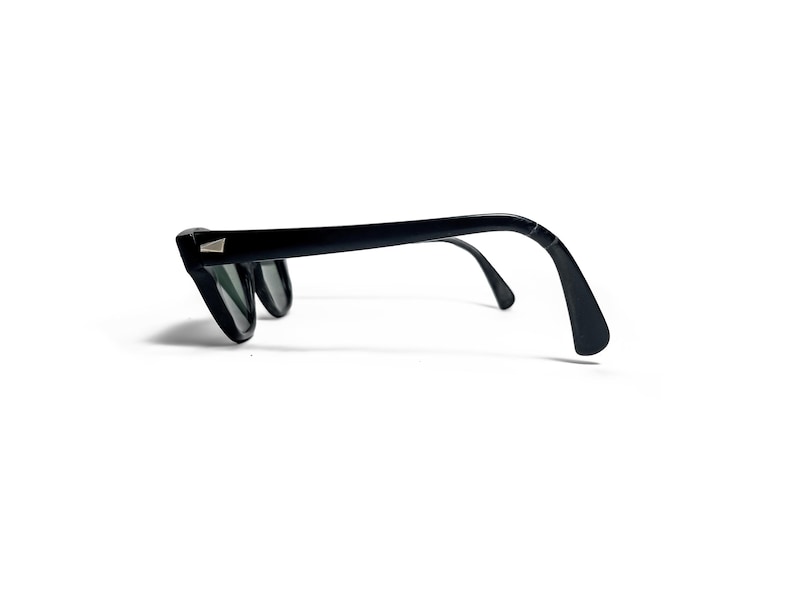 May include: Black sunglasses with a classic design. The frames are thick and angular, with a small silver accent on the temples. The lenses are dark, and the arms curve down to fit over the ears. A stylish accessory.