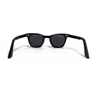 May include: Black sunglasses with dark lenses. The sunglasses have a classic, rectangular frame and are set against a white background. The arms of the sunglasses are extended, showing the full shape.