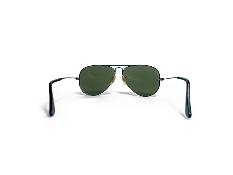 May include: Aviator sunglasses with a black metal frame and green lenses. The classic teardrop-shaped lenses are set in a thin, black frame with a double bridge. The temples are also black.