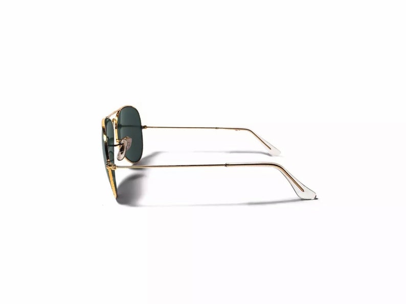 May include: Gold aviator sunglasses with green lenses. The sunglasses are shown from the side.