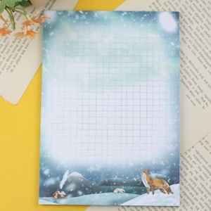 Könnte beinhalten: Ein blaues und weißes kariertes Notizbuch mit einer Winterszene. Die Szene zeigt einen Fuchs, ein kleines Haus und eine verschneite Landschaft. Das Notizbuch ist perfekt zum Notieren, Schreiben von Listen oder Skizzieren.