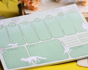 May include: A green weekly planner with a grid layout and illustrations of animals. The planner has sections for Monday, Tuesday, Wednesday, Thursday, Friday, Saturday, and Sunday, as well as sections for notes, habits, and next week.