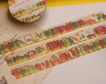 May include: A roll of washi tape with a Christmas book theme. The tape features a bookshelf with books, lights, and decorations. The text on the tape reads "Christmas Book".