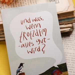Peut inclure: Carte de vœux avec le texte allemand « und was, wenn trotzdem alles gut wird ? » dans une bulle de dialogue. Une pie est perchée sur un poteau en bois, avec une maison rouge en arrière-plan. La carte est sur une surface jaune.