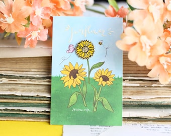 May include: A card with a blue background and a drawing of three sunflowers. The card says "Sunflower" and "Zenownia".