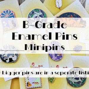 Könnte beinhalten: Eine Sammlung von Emaille-Pins mit verschiedenen Designs, darunter eine Katze, ein Vogel und ein Buch. Die Pins sind alle klein und rund und auf einem weißen Hintergrund angeordnet. Der Text "B-Grade Enamel Pins Minipins" ist in schwarzen Buchstaben oben im Bild geschrieben. Der Text "My bigger pins are in a separate listing" ist in schwarzen Buchstaben unten im Bild geschrieben.