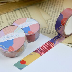 May include: Two rolls of colorful washi tape with abstract patterns. The tape features a mix of pink, blue, yellow, and gold colors. The text on the tape reads "Colorful Pattern" and "15mm washi tape".