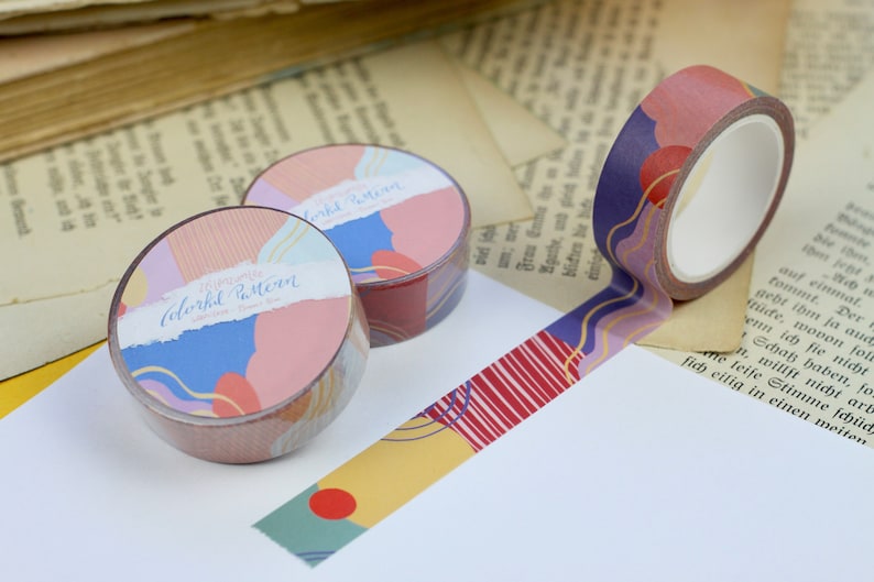 May include: Two rolls of colorful washi tape with abstract patterns. The tape features a mix of pink, blue, yellow, and gold colors. The text on the tape reads "Colorful Pattern" and "15mm washi tape".