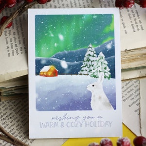 Cartolina - Coniglio nella neve - Aurora boreale - Paesaggio montano con capanna - Vacanza calda e accogliente - Natale invernale - Illustrazione personale