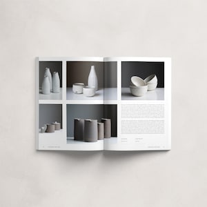 May include: An open book displaying a collection of ceramic pottery. The book features images of white and grey ceramic vases, bowls, and cups. The text on the page reads "Crafted By".