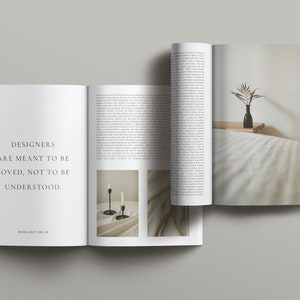 May include: Open magazine with a quote about designers being loved, not understood. The quote is attributed to Margaret Olsen. The magazine features a photo of two black candlesticks on a white surface and a photo of a vase with dried branches on a white bedspread.