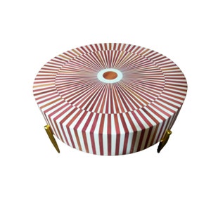 Può includere: Tavolino da caffè rotondo con piano a strisce bianche e rosse e gambe in metallo dorato. Il piano ha un design circolare al centro.