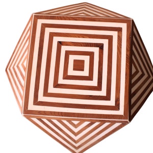 Puede incluir: Una tapa de mesa de madera con un diseño geométrico de rayas marrones y blancas alternadas. La tapa de la mesa tiene forma de octógono.