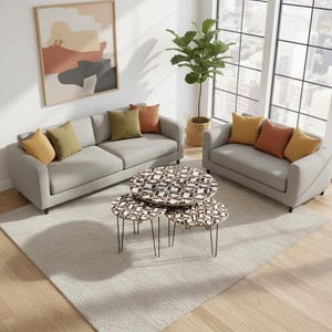 Puede incluir: Una moderna sala de estar con dos sofás grises y un sofá, adornados con coloridos cojines. Un juego de tres mesas de centro estampadas con patas negras se encuentra sobre una alfombra neutra. Una gran ventana y una planta en maceta completan la decoración de la habitación.