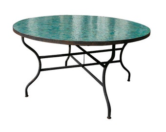 Op de afbeelding: Ronde tafel met een tafelblad van tealblauwe mozaïektegels en een zwart metalen onderstel. De tafel heeft een eenvoudig, elegant ontwerp met een gebogen onderstel.