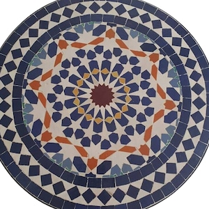 Puede incluir: Una tapa de mesa redonda con un diseño de mosaico con patrones geométricos azules, blancos, naranjas y rojos. El centro de la tapa de la mesa tiene un diseño de estrella.