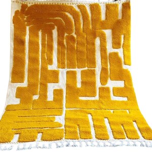 May include: A yellow and white geometric patterned rug with a fringe border.