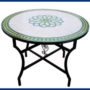 Op de afbeelding: Ronde mozaïektafel met een groen en geel bloemenontwerp. De tafel heeft een zwart metalen onderstel met een decoratief scrollontwerp.