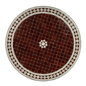 May include: A round table top with a brown mosaic tile design and a white border. The center of the table has a white starburst design.