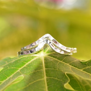 Pode incluir: Um par de anéis de chevron de prata empilhados um em cima do outro. Os anéis são martelado e têm um acabamento texturizado.