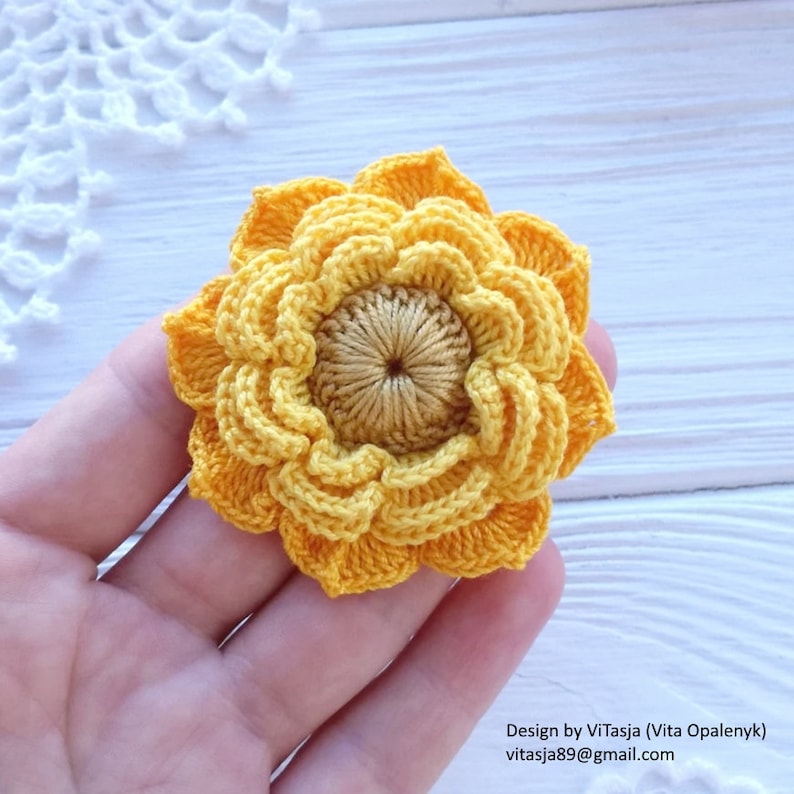 Puede incluir: Un girasol amarillo tejido a crochet con un centro marr&oacute;n. La flor tiene un di&aacute;metro de aproximadamente 5 cm.