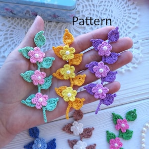 May include: A set of crocheted flower sprigs in various colors, including green, yellow, purple, blue, brown, and white. The sprigs are made with a single pearl bead in the center of each flower. The word "Pattern" is written in black text on a white background.