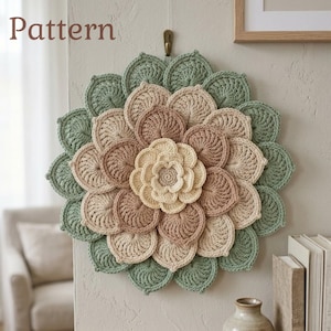 Puede incluir: Un tapiz de pared floral hecho a mano con ganchillo. La pieza presenta una flor central en crema, rodeada de capas de pétalos en tonos verdes, beige y marrón. La palabra "Pattern" es visible en la esquina superior izquierda.