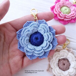 Puede incluir: Un conjunto de tres llaveros de flores de ganchillo en azul, rosa y crema. Las flores est&aacute;n hechas con una variedad de puntos y tienen un aspecto delicado y femenino. Los llaveros est&aacute;n unidos a anillos de metal dorado.