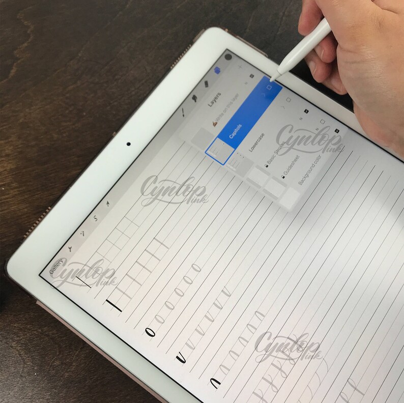 K&ouml;nnte beinhalten: Ein digitales Tablet mit einem Stift, das ein handschriftliches Alphabet-&Uuml;bungsblatt mit Linien und eine digitale Zeichen-App-Oberfl&auml;che mit Ebenen, Kleinbuchstaben, grundlegenden Richtlinien und Hintergrundfarbenoptionen zeigt.