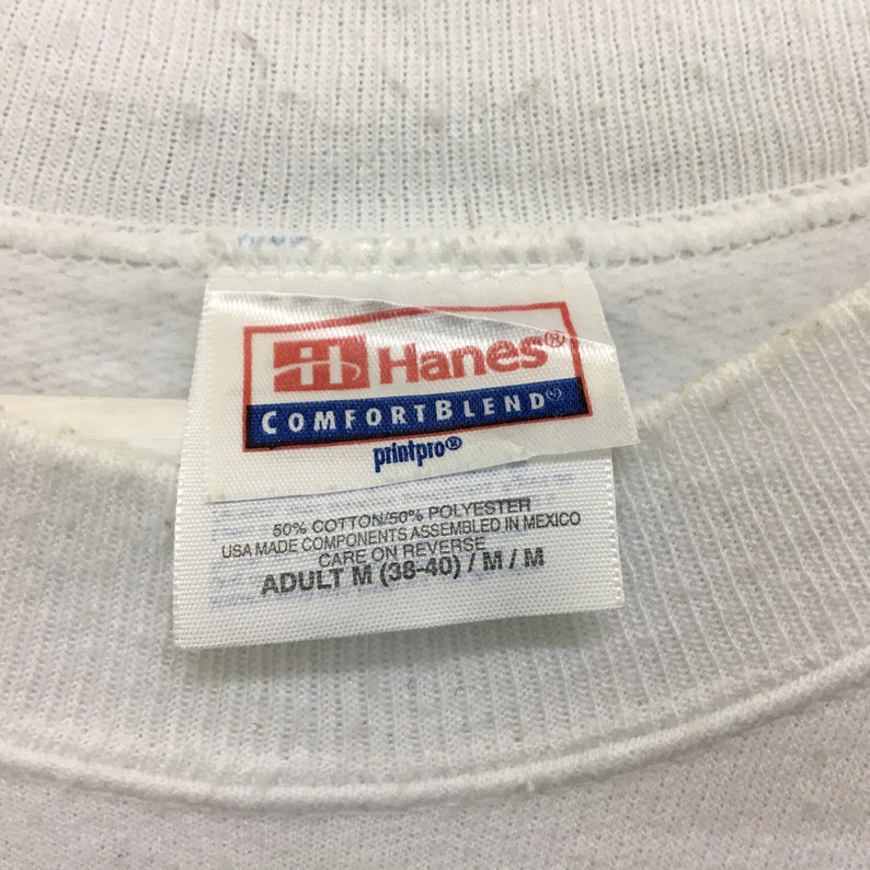 May include: White Hanes Comfortblend sweatshirt tag with the text "Hanes Comfortblend printpro 50% Cotton/50% Polyester USA Made Components Assembled in Mexico Care on Reverse Adult M (38-40)/M/M"