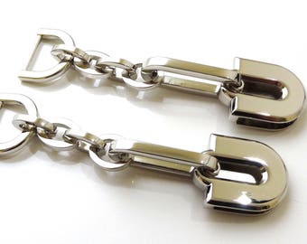 May include: Two silver metal chain links with a U-shaped clasp at the end of each chain.