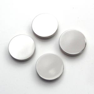 May include: Four silver-coloured round buttons with a smooth, shiny surface.