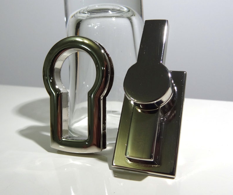 May include: Two silver-toned metal keyhole covers. One is a simple keyhole cover, the other is a rectangular cover with a round keyhole cover on top.