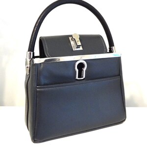 May include: A dark gray leather handbag with a silver top clasp and a silver keyhole detail. The bag has a black leather top handle.