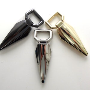 May include: Three metal pointy tip swivel hooks in black, gold, and silver finishes. Each hook has a square loop opening.