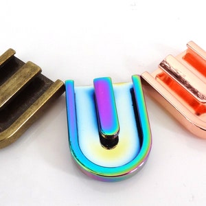 May include: Three metal U-shaped buckles in different finishes: antique brass, iridescent rainbow, and copper.