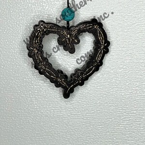 May include: Black metal heart-shaped ornament with a gold wire design and a turquoise bead hanging from a black string.