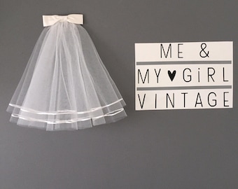 Puede incluir: Un velo de novia blanco con un lazo de satén y dos filas de ribete de satén. Un cartel blanco con texto negro dice "ME & MY ♥ GIRL VINTAGE".