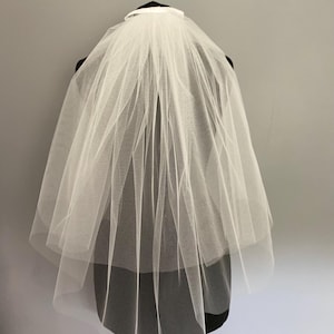 May include: A white single-tier bridal veil with a satin ribbon trim. The veil is made of soft tulle and is designed to be worn with a comb.