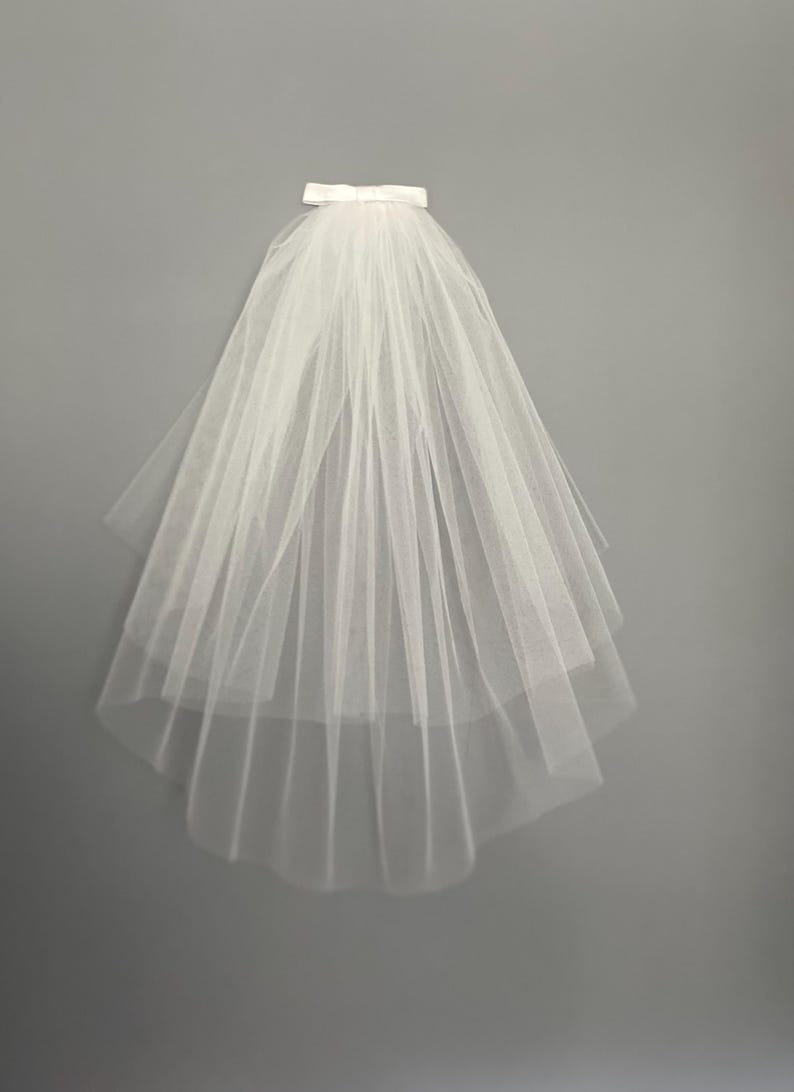 May include: A white tulle bridal veil with a satin ribbon at the top.