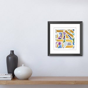 May include: A framed print of a colorful abstract design featuring gold Hebrew letters on a white background.