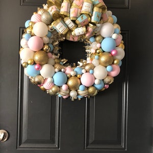 May include: A pink and blue Christmas wreath with gold ornaments and a bow with the text "Believe in Magic" and "Believe in Dreams".