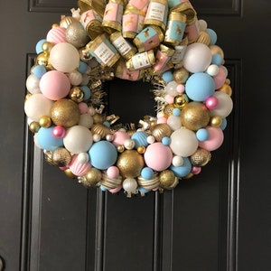 May include: A pink, blue, and gold Christmas wreath with a bow that says "Just Believe in Your Dreams".