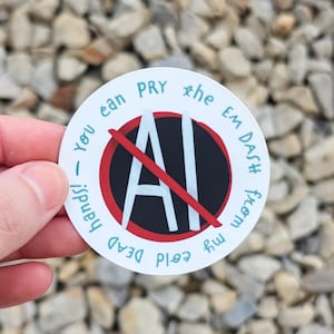 Può includere: Un adesivo rotondo con la scritta "You can pry the EM DASH from my cold dead hands!". La parola "AI" è barrata con una linea rossa. L'adesivo ha uno sfondo bianco con dettagli neri e rossi.