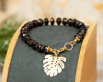 Gilded bracelet with garnet stone, gold plated bracelet with garnet stone, bracelet with monstera leaf pendant, black and gold jewelry