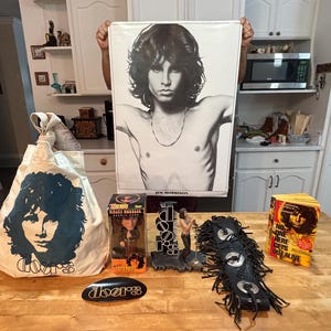 Bolsa sorpresa navideña de Jim Morrison: bolso; cabezón; figura de acción; correa de guitarra con flecos negros y adornos; póster; libro: Nadie aquí sale vivo.