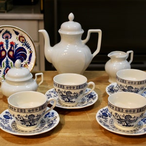May include: A white tea set with blue and white floral designs. The set includes a teapot, sugar bowl, creamer, and four teacups and saucers.