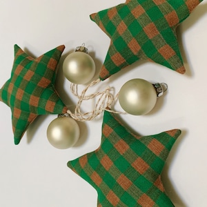 May include: A string of green and brown plaid fabric stars with white and gold ornaments.