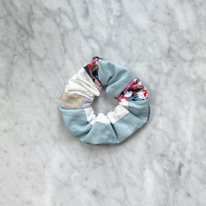 May include: A blue, white, and floral patterned scrunchie for hair.